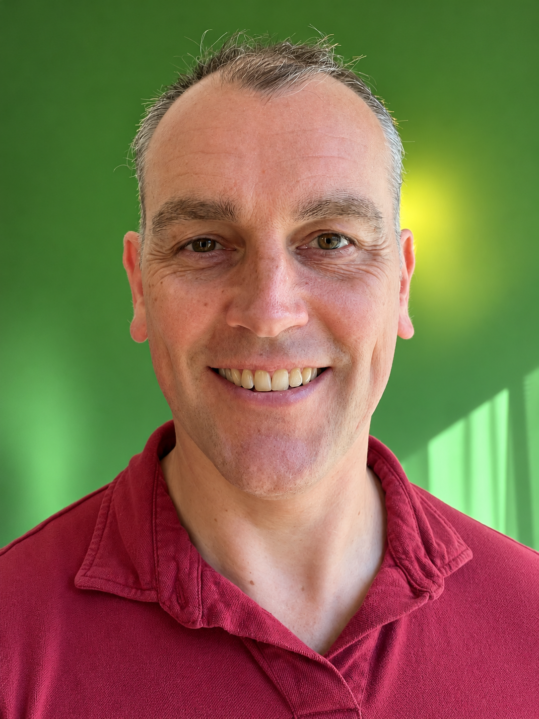 Portret van Jeroen Pouw, glimlachend in een rode polo